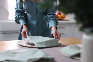 Woman setting table for dinner at home, closeup