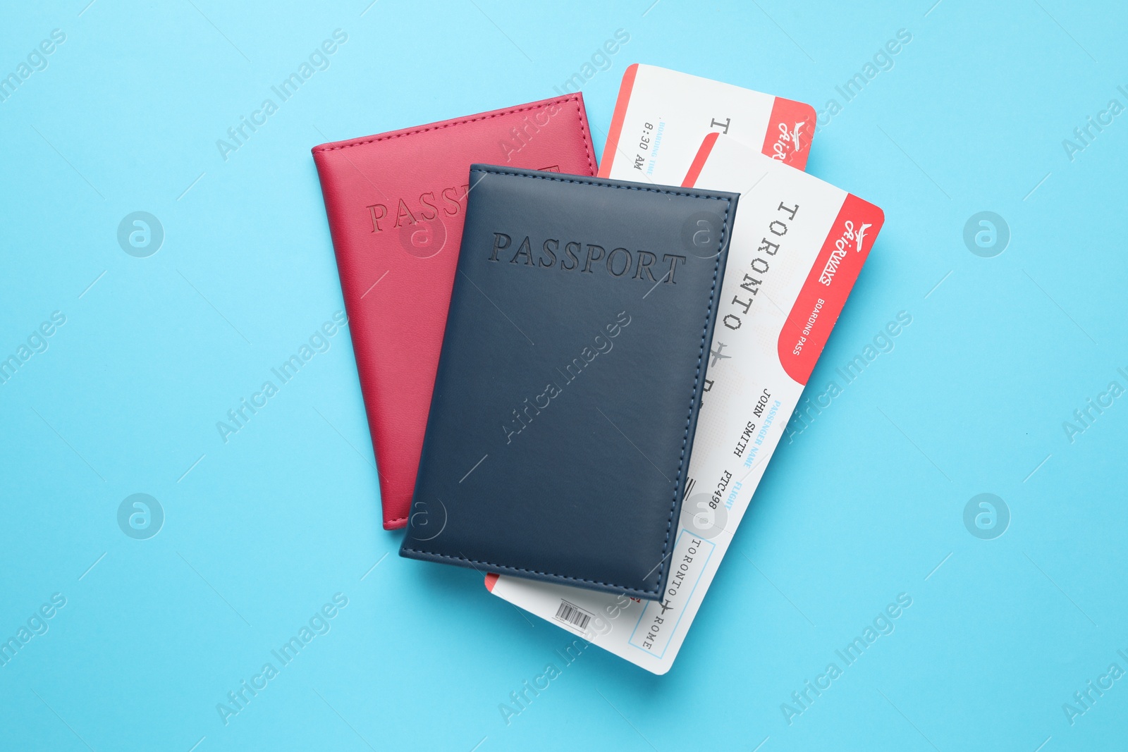 Photo of Travel agency. Flight tickets and passports on light blue background, top view