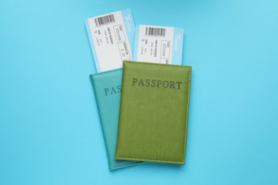 Photo of Travel agency. Flight tickets and passports on light blue background, top view