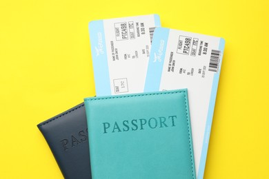 Photo of Travel agency. Flight tickets and passports on yellow background, top view