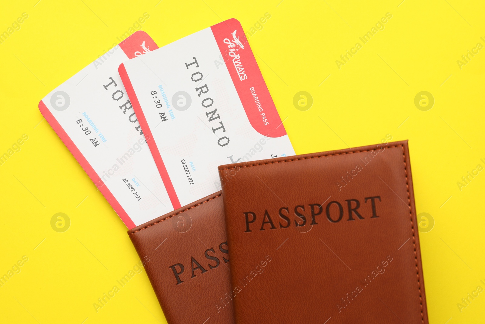 Photo of Travel agency. Flight tickets and passports on yellow background, top view