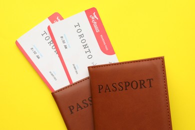 Photo of Travel agency. Flight tickets and passports on yellow background, top view