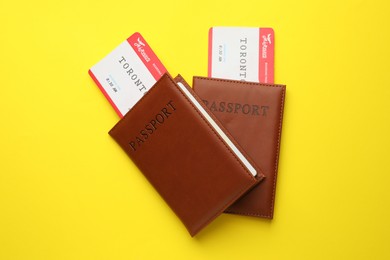 Photo of Travel agency. Flight tickets and passports on yellow background, top view