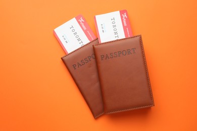 Photo of Travel agency. Flight tickets and passports on orange background, top view