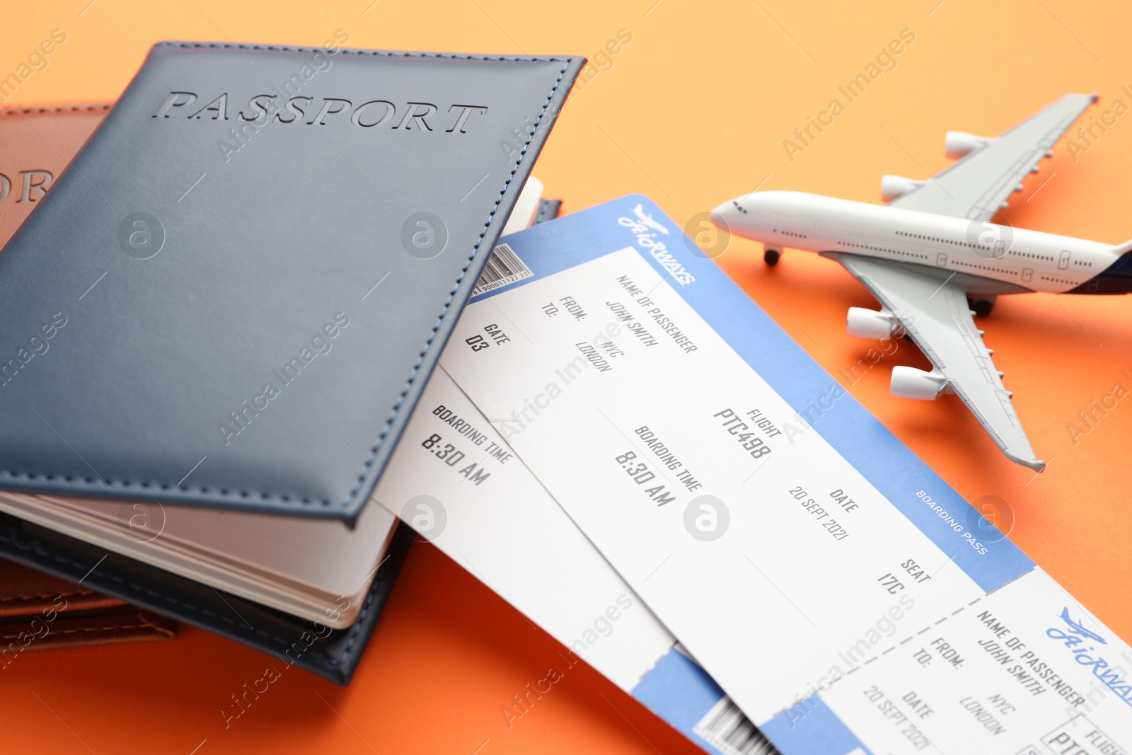 Photo of Travel agency. Flight tickets, passports and plane model on orange background, closeup