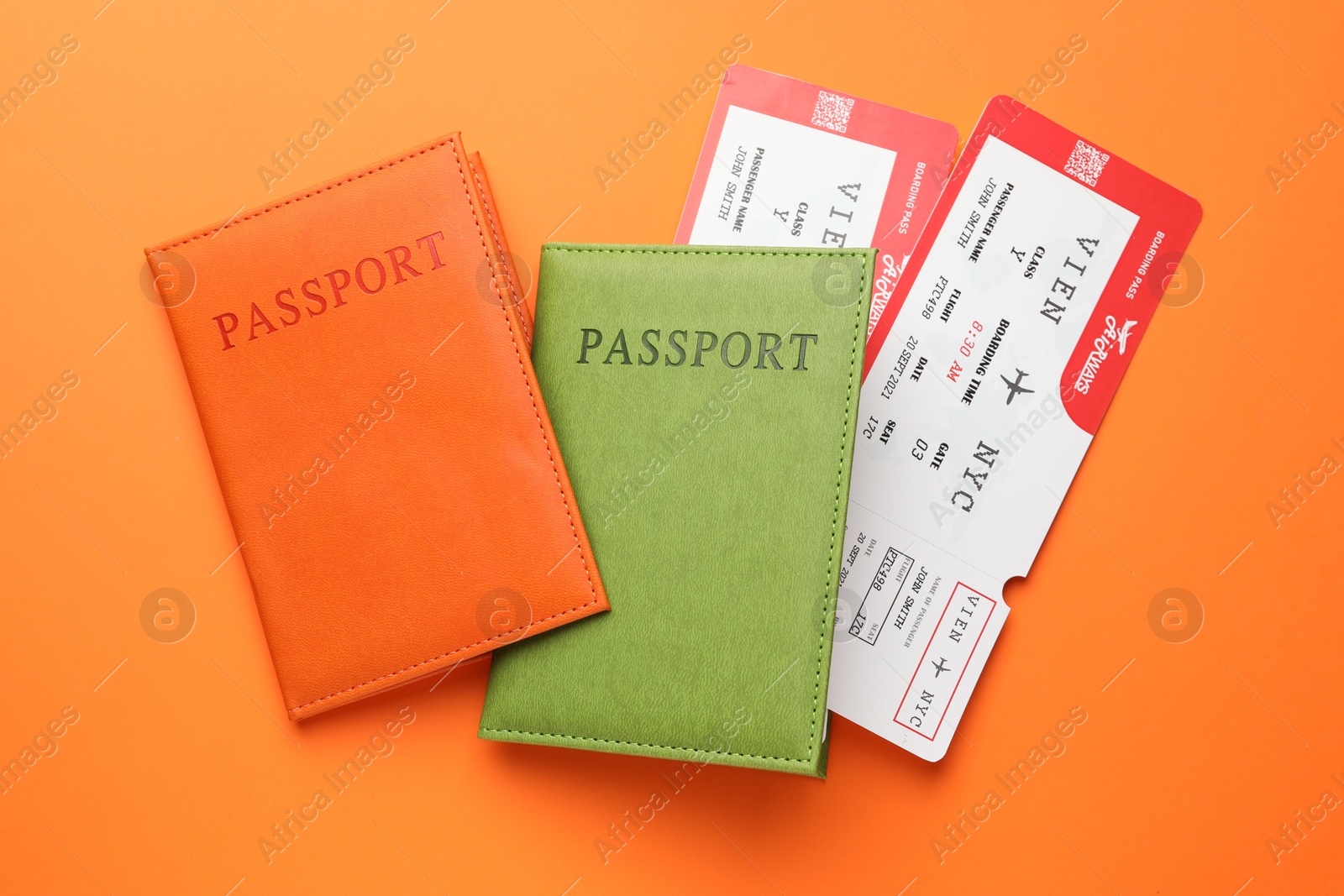 Photo of Travel agency. Flight tickets and passports on orange background, flat lay