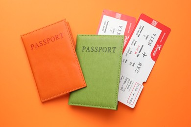 Photo of Travel agency. Flight tickets and passports on orange background, flat lay