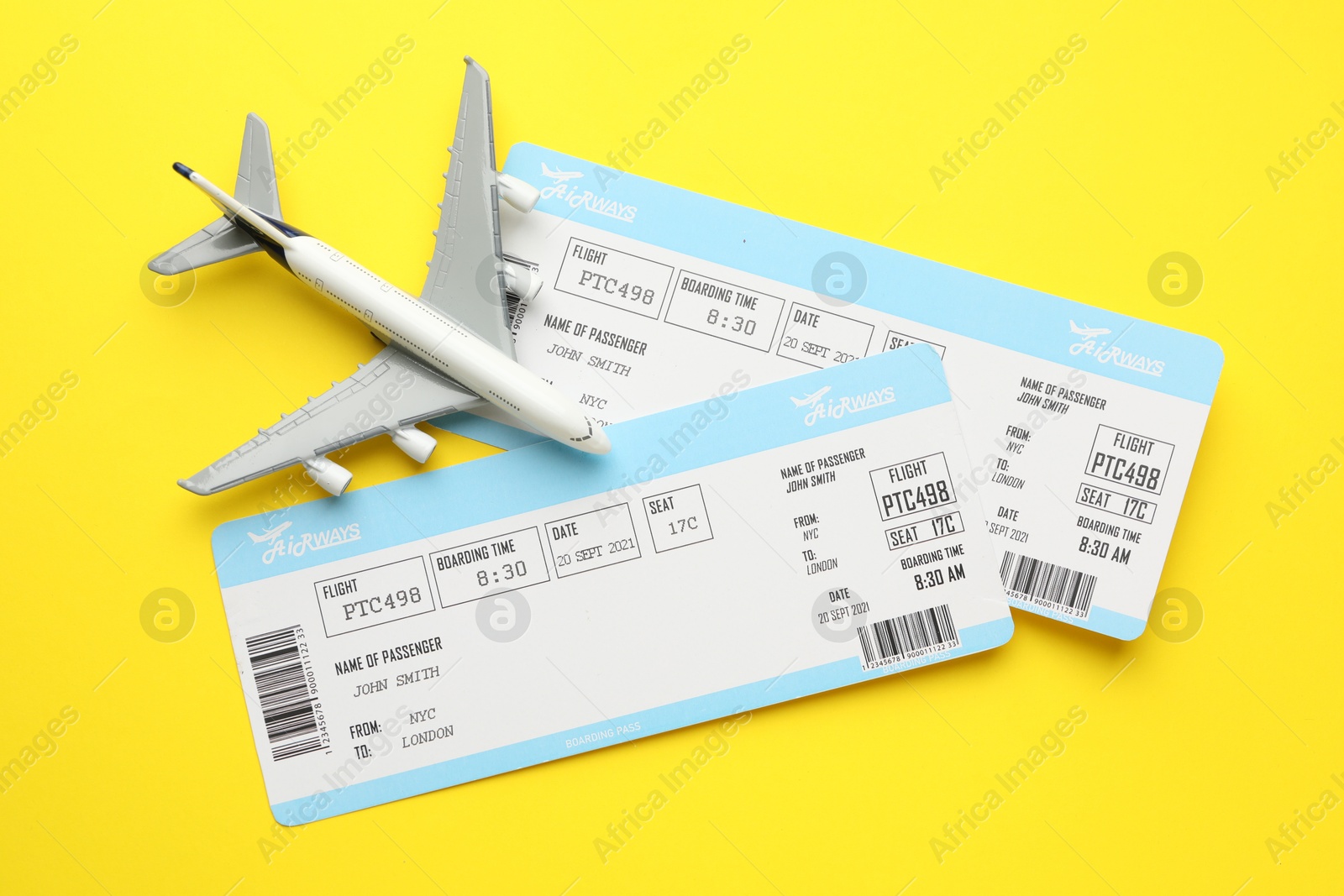 Photo of Travel agency. Flight tickets and plane model on yellow background, flat lay