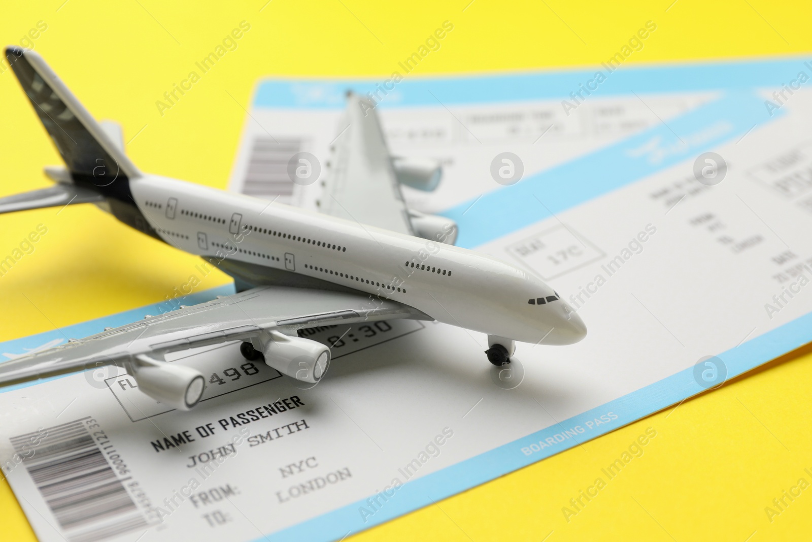 Photo of Travel agency. Flight tickets and plane model on yellow background, closeup