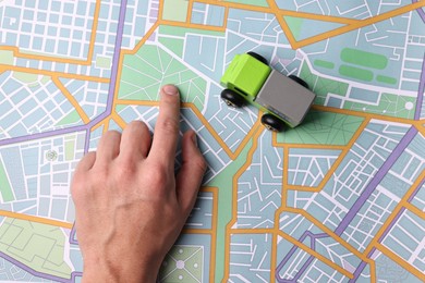 Photo of Woman pointing at city map with toy truck, closeup. Logistics concept