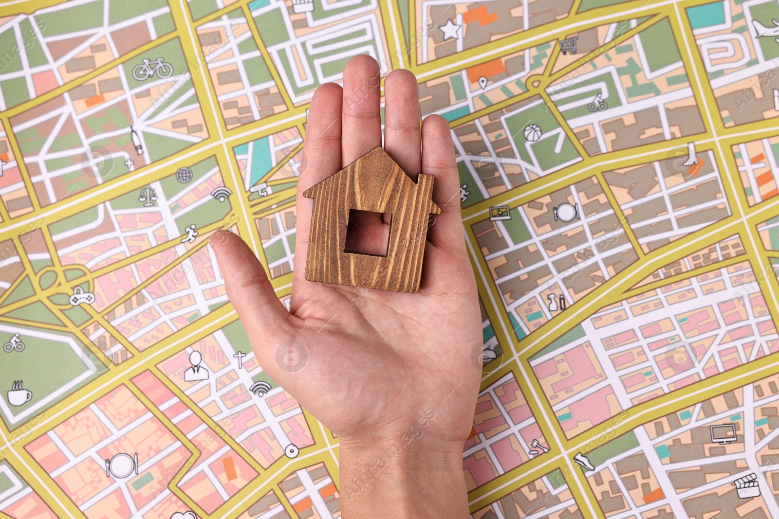 Photo of Woman holding wooden house model on city map, top view. Accommodation search