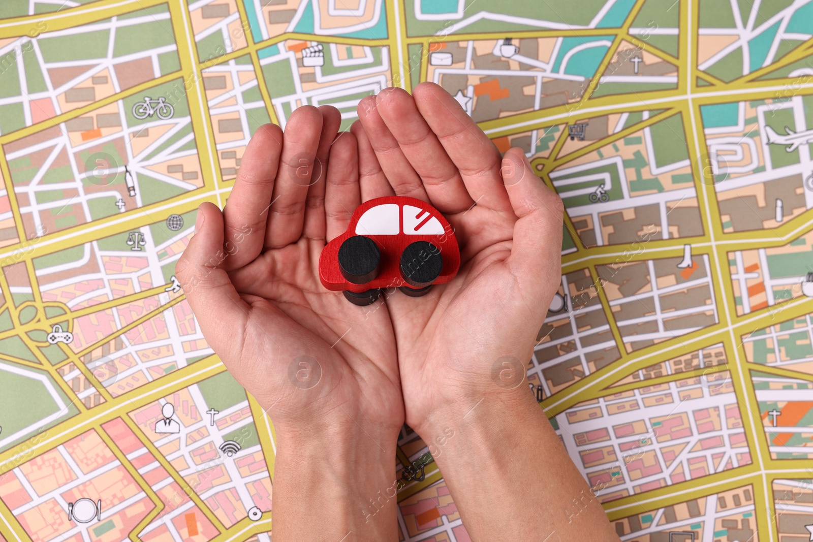 Photo of Woman holding red toy car on city map, top view. Road trip