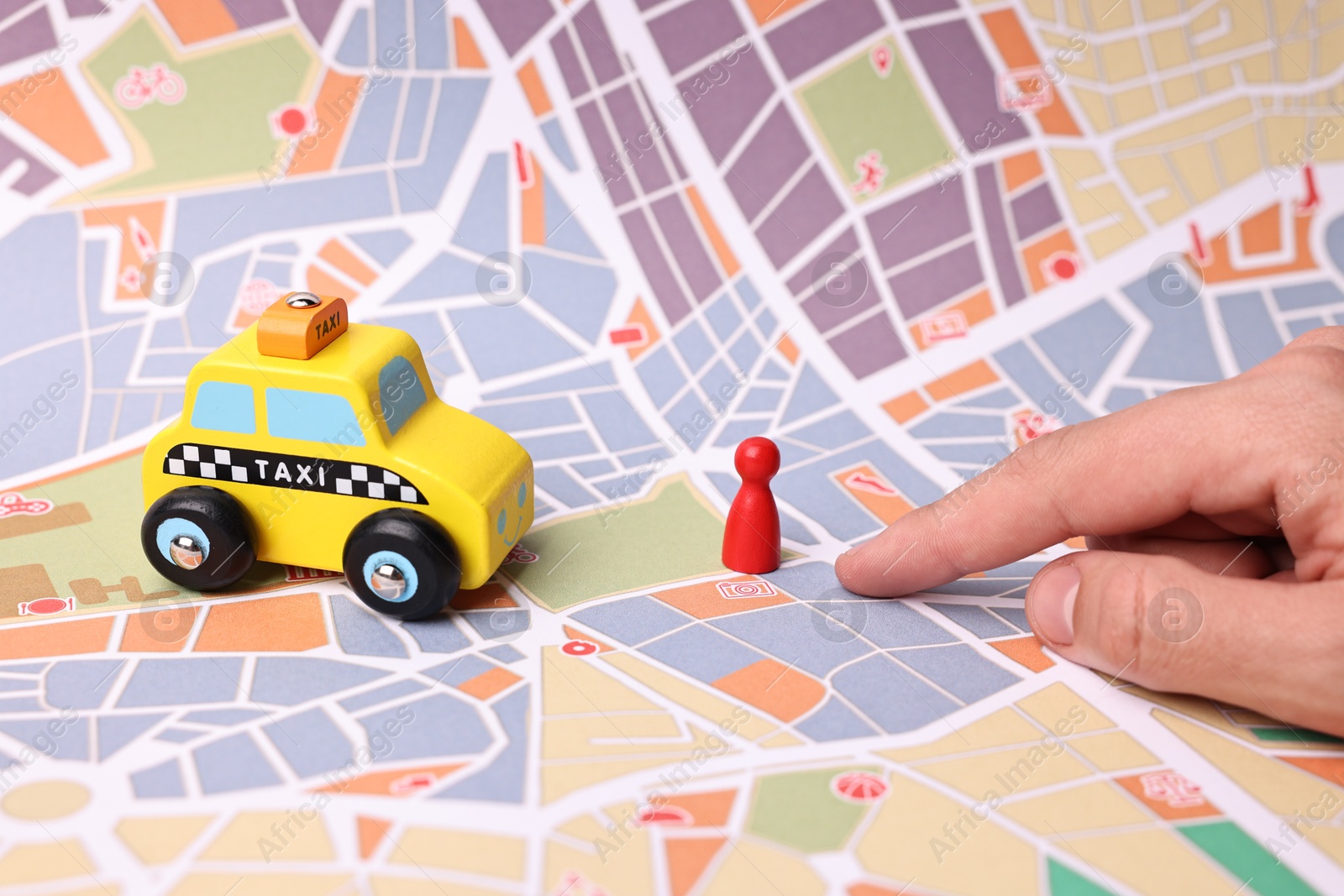 Photo of Woman pointing at city map with yellow taxi car and human figure, closeup