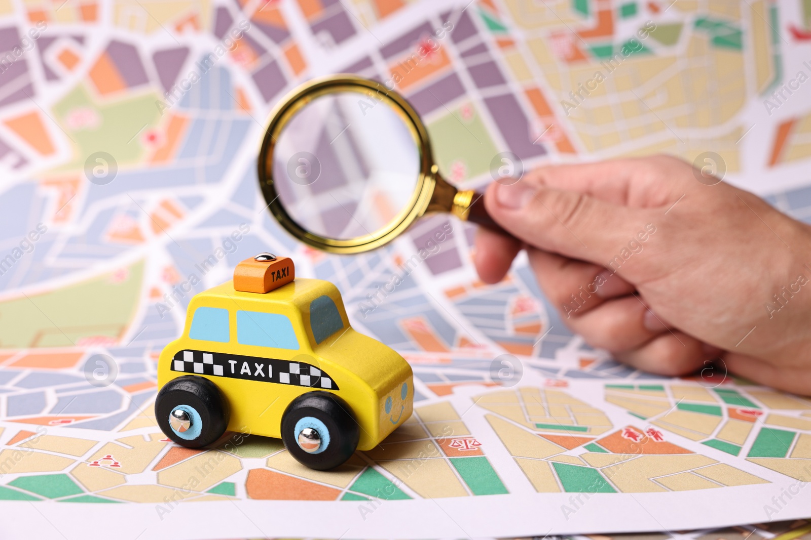 Photo of Woman looking at city map through magnifying glass, focus on yellow taxi car