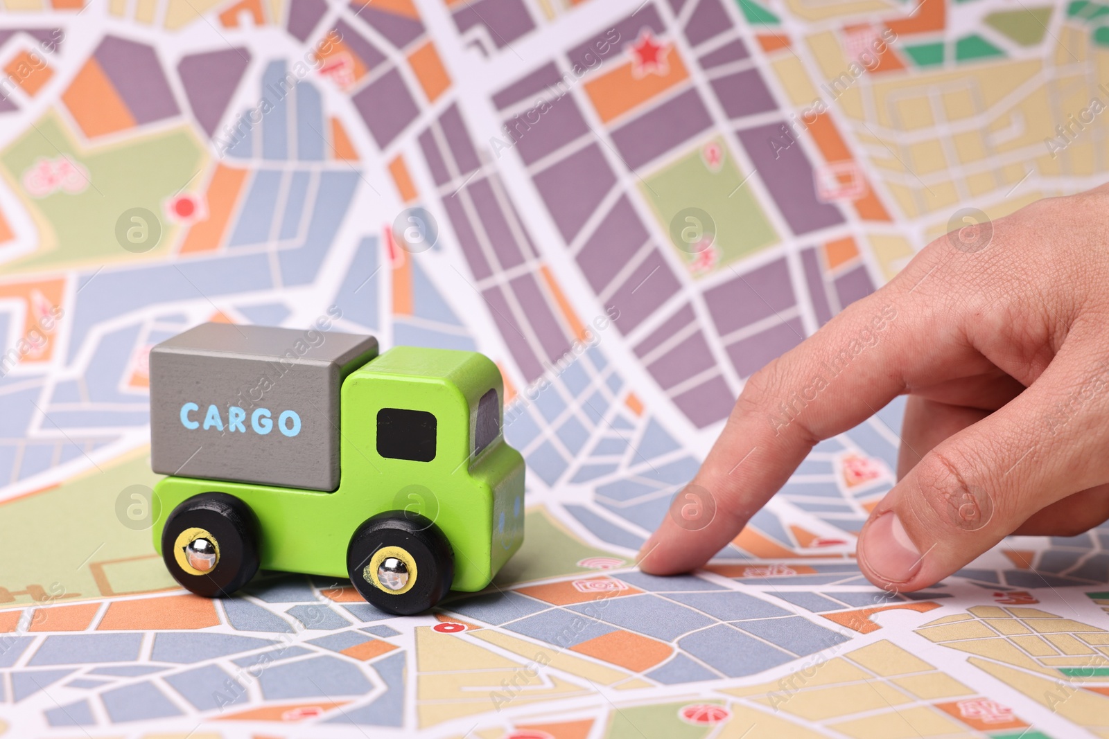 Photo of Woman pointing at city map with toy truck, closeup. Logistics concept