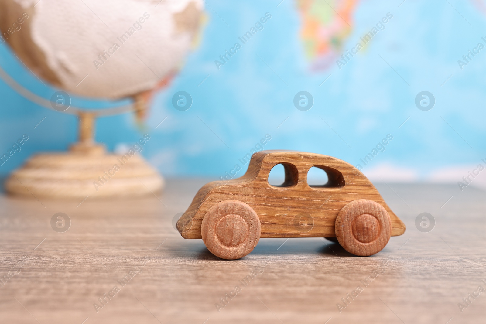 Photo of Toy car and globe on wooden table against world map, closeup. Road trip