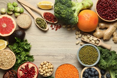 Photo of Frame of different superfood products on wooden table, flat lay. Space for text