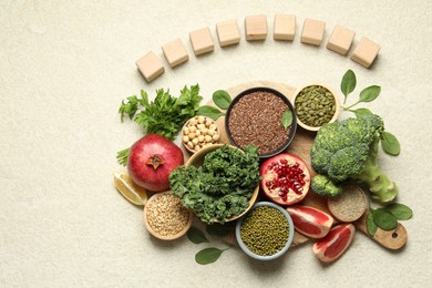 Photo of Different superfood products and blank cubes on light table, top view. Space for text