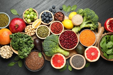 Photo of Different superfood products on black table, flat lay