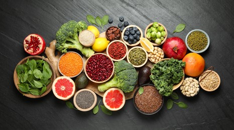 Photo of Different superfood products on black table, flat lay