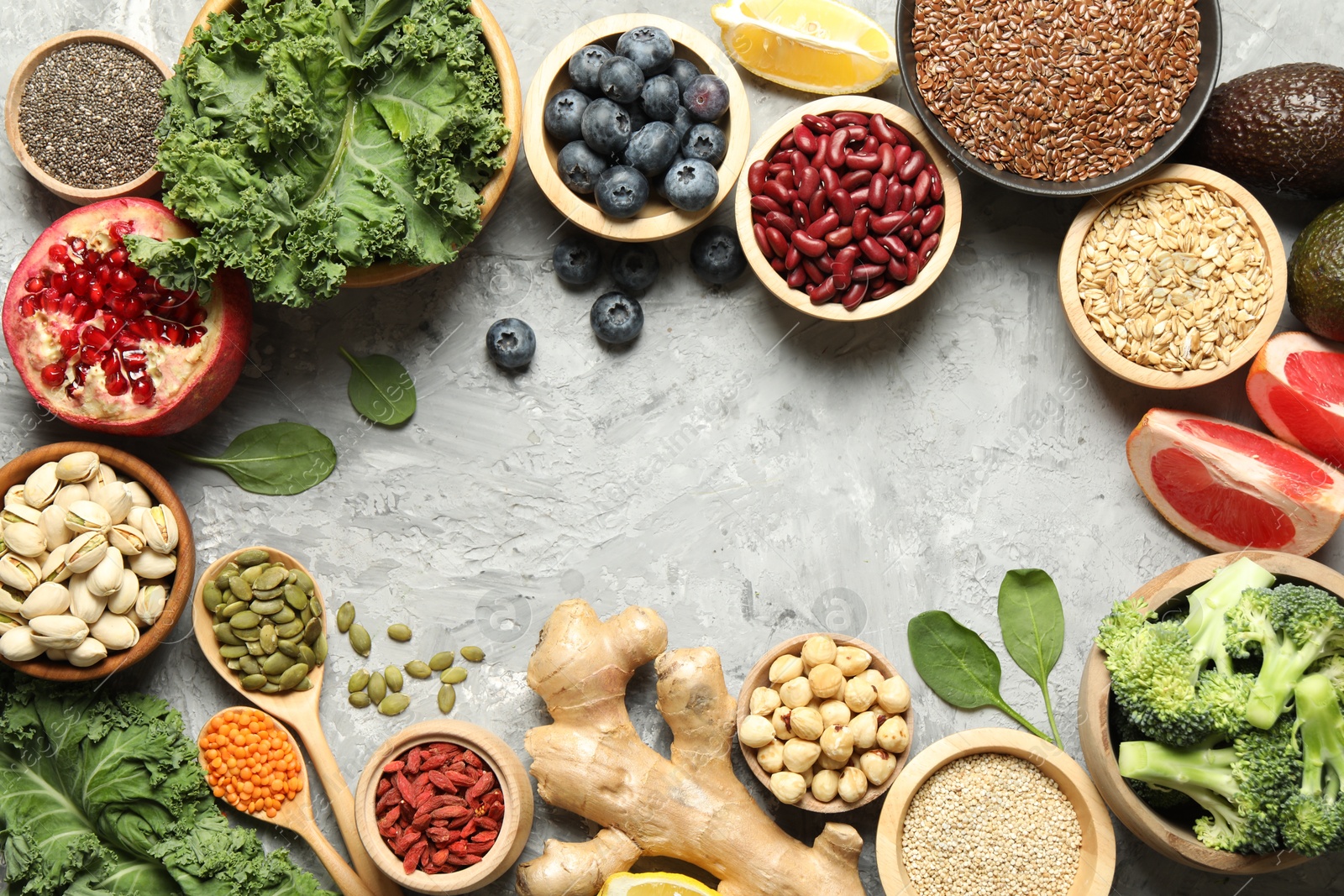 Photo of Frame of different superfood products on grey table, flat lay. Space for text