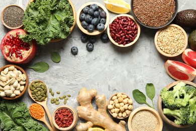 Photo of Frame of different superfood products on grey table, flat lay. Space for text