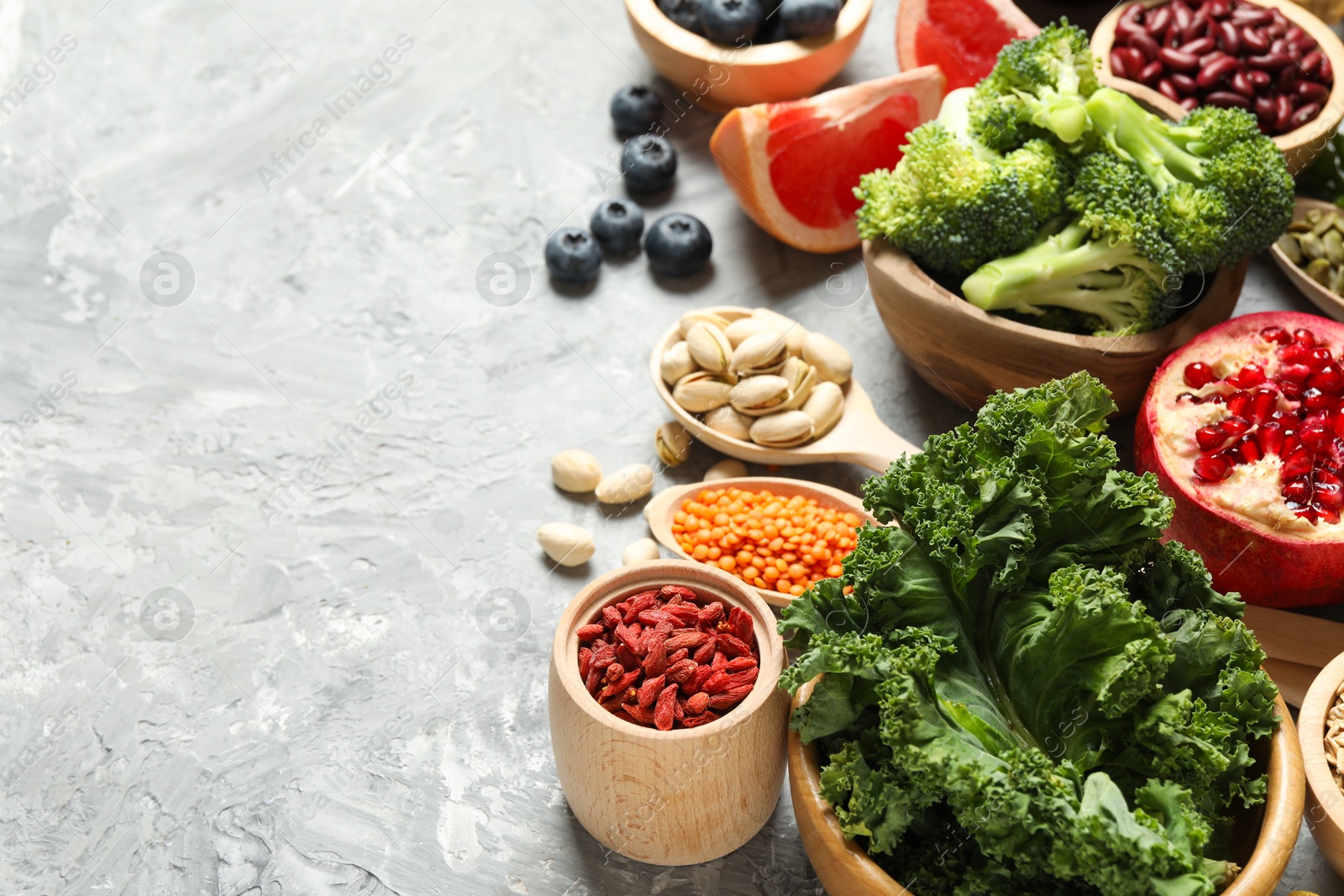 Photo of Different superfood products on grey textured table. Space for text