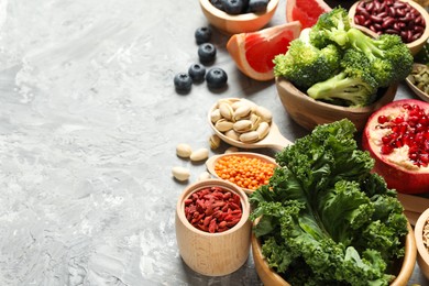 Photo of Different superfood products on grey textured table. Space for text