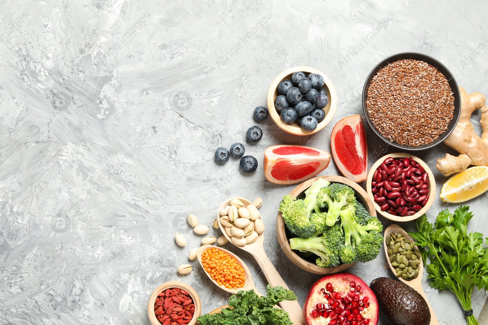 Photo of Different superfood products on grey table, flat lay. Space for text