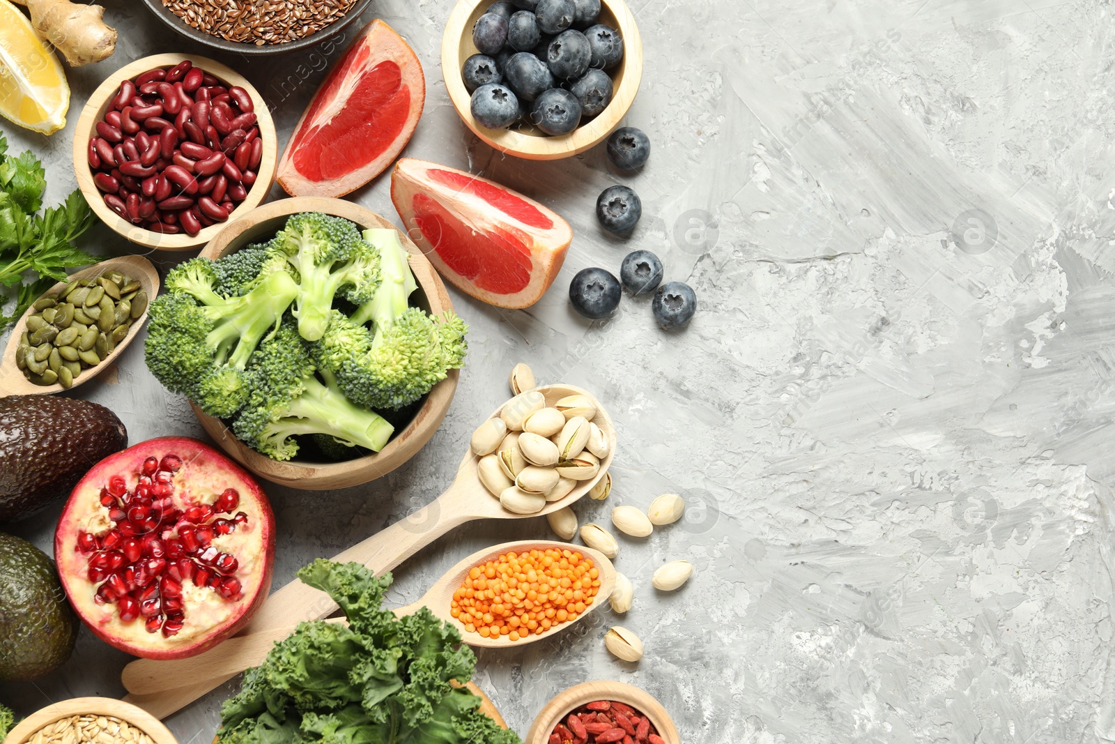 Photo of Different superfood products on grey table, flat lay. Space for text