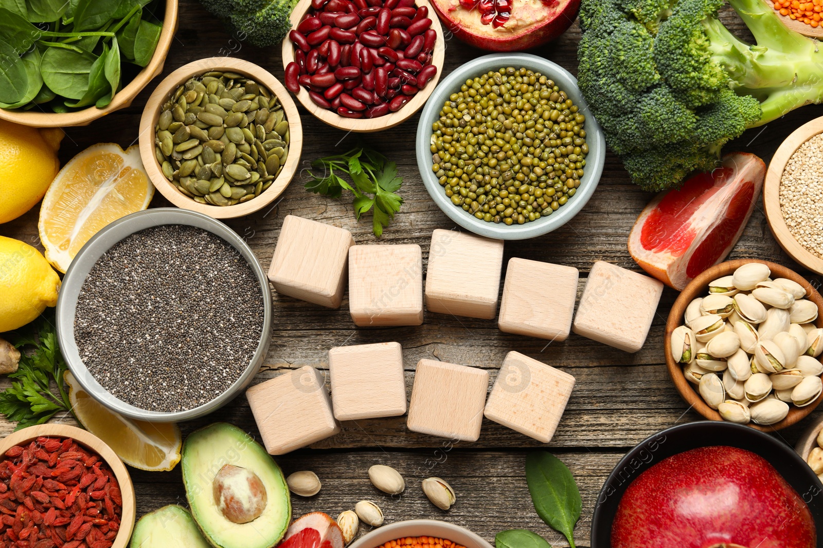 Photo of Different superfood products and blank cubes on wooden table, flat lay. Space for text