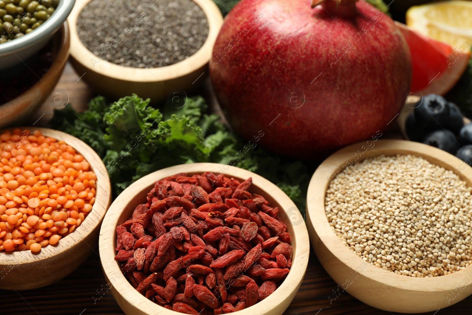 Photo of Different superfood products on wooden table, closeup