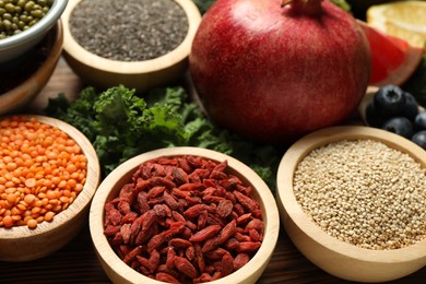 Photo of Different superfood products on wooden table, closeup