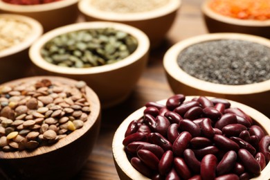 Photo of Different superfood products in bowls on wooden table, closeup