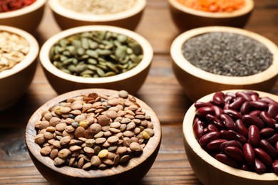 Photo of Different superfood products in bowls on wooden table, closeup