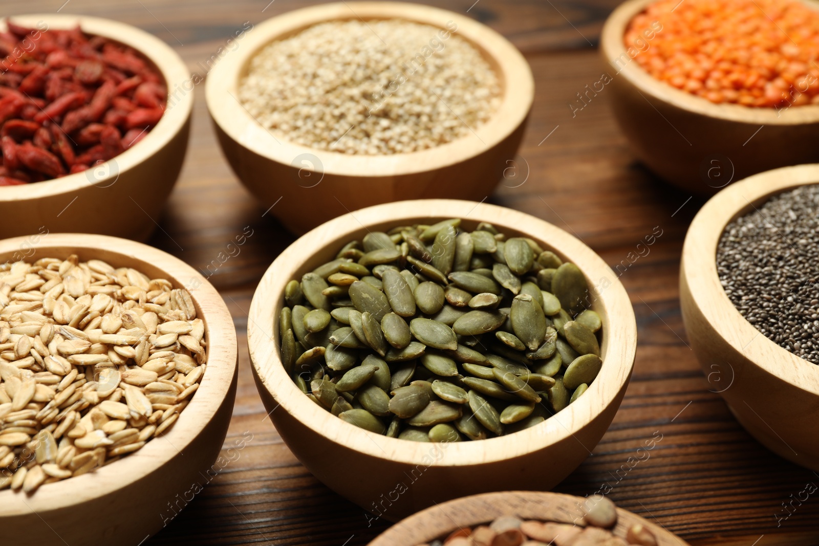 Photo of Different superfood products in bowls on wooden table, closeup