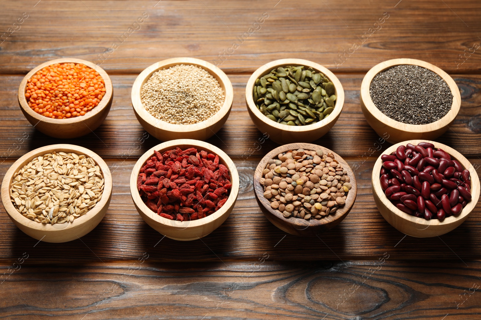 Photo of Different superfood products in bowls on wooden table