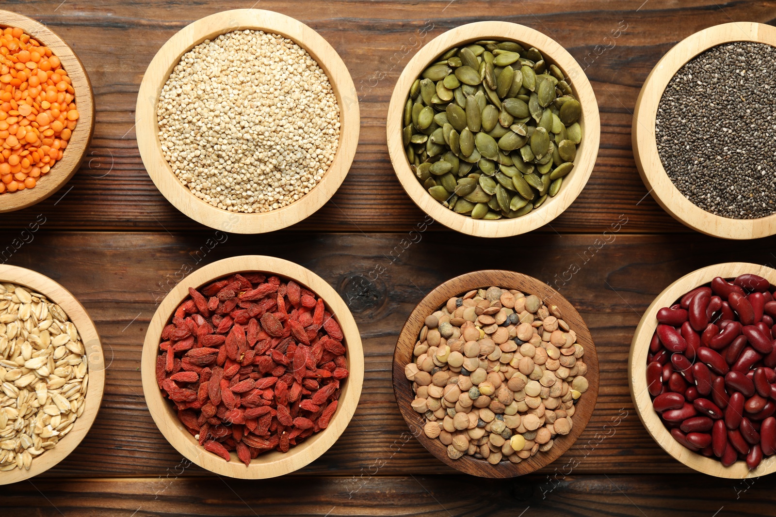 Photo of Different superfood products in bowls on wooden table, flat lay