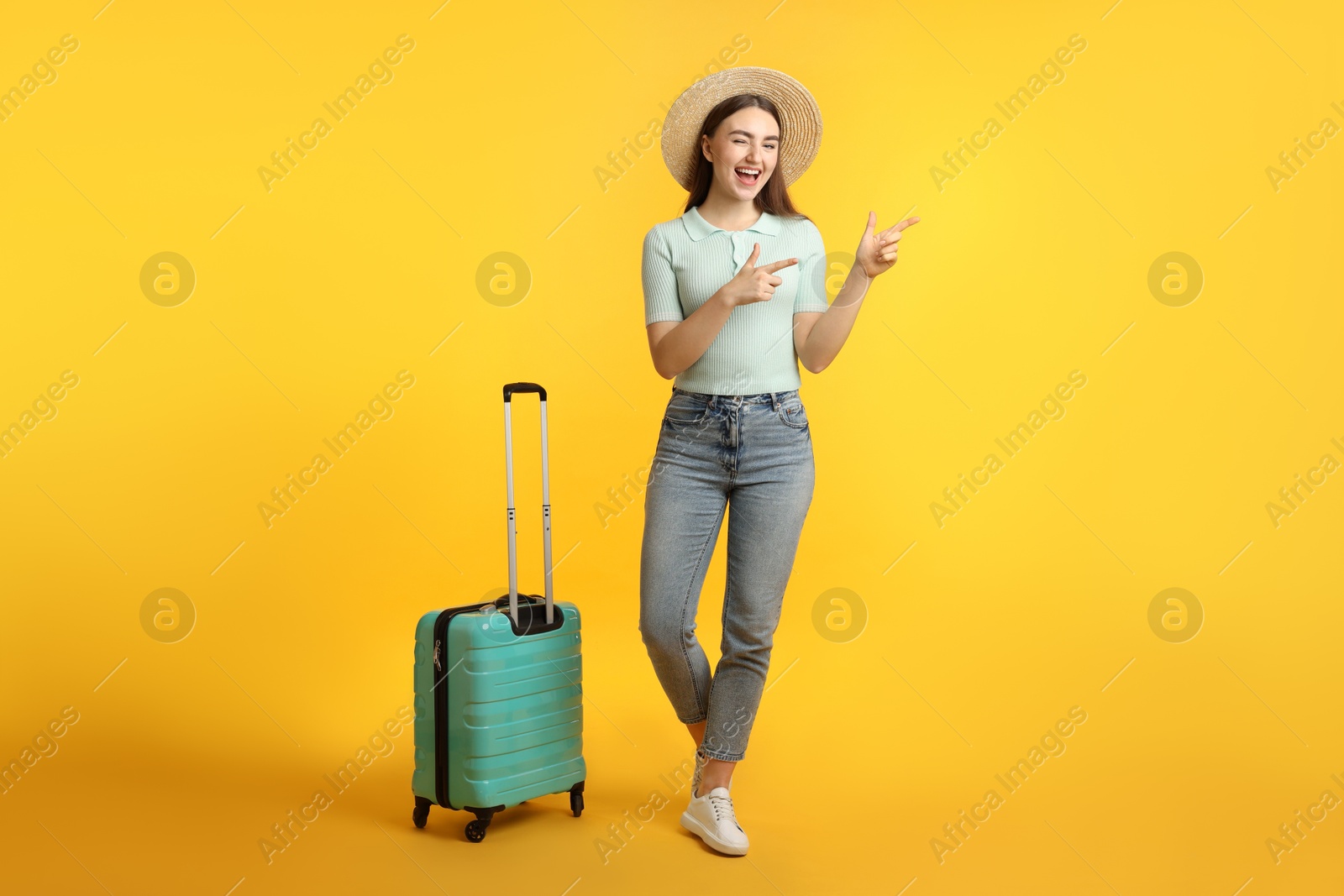 Photo of Woman in straw hat with suitcase on orange background