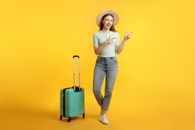 Photo of Woman in straw hat with suitcase on orange background