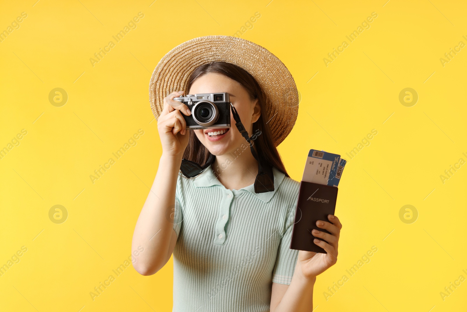 Photo of Woman with tickets, passport and vintage camera on orange background