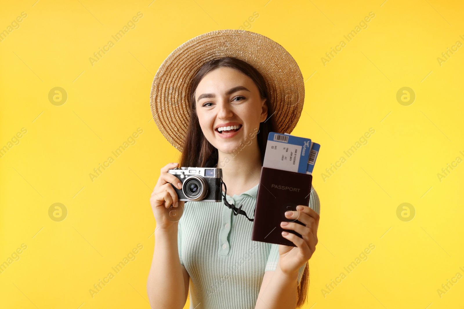 Photo of Woman with tickets, passport and vintage camera on orange background