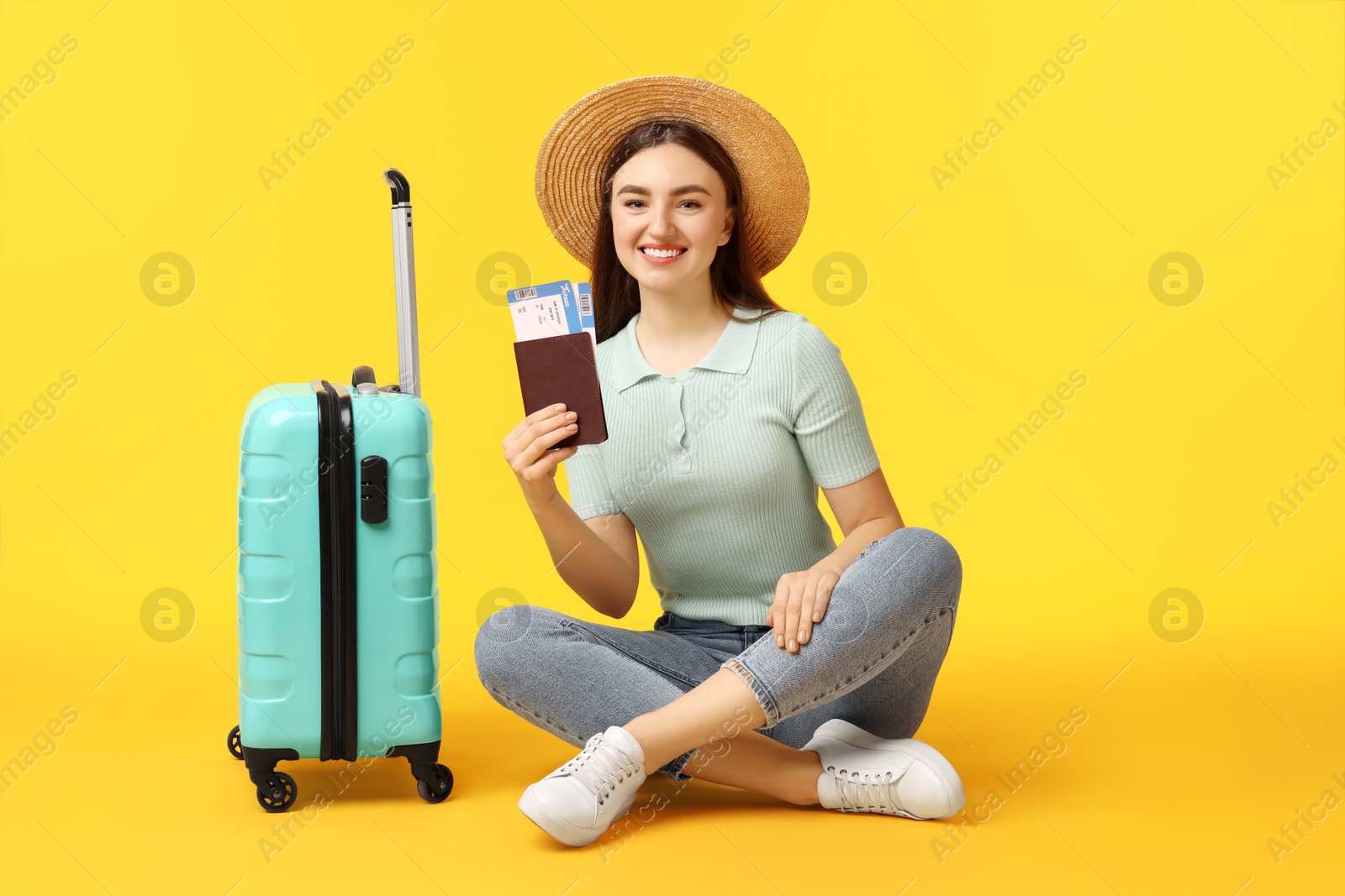 Photo of Woman with tickets, passport and suitcase on orange background