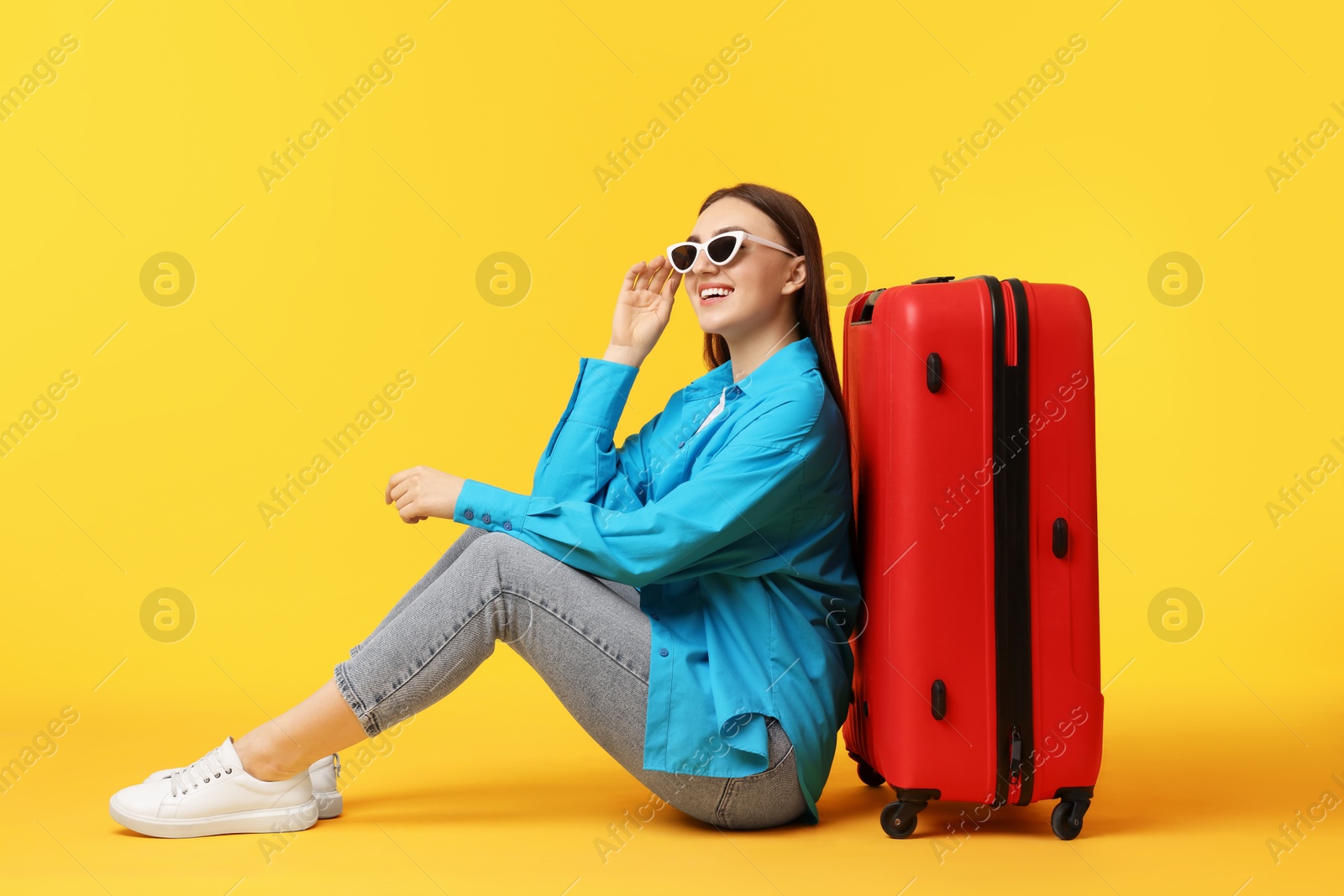 Photo of Woman with suitcase wearing sunglasses on orange background