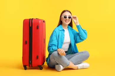 Photo of Woman with suitcase wearing sunglasses on orange background