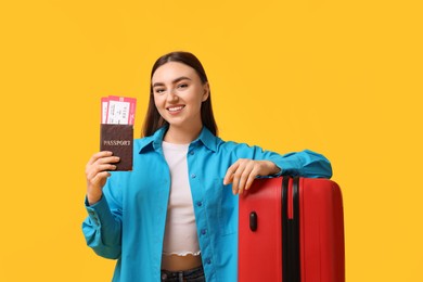 Photo of Woman with tickets, passport and suitcase on orange background