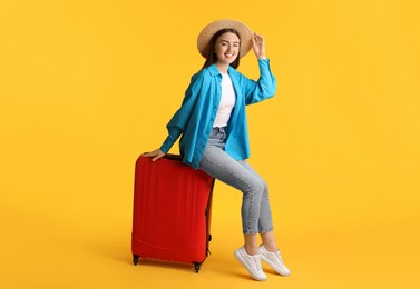 Photo of Woman in straw hat with suitcase on orange background