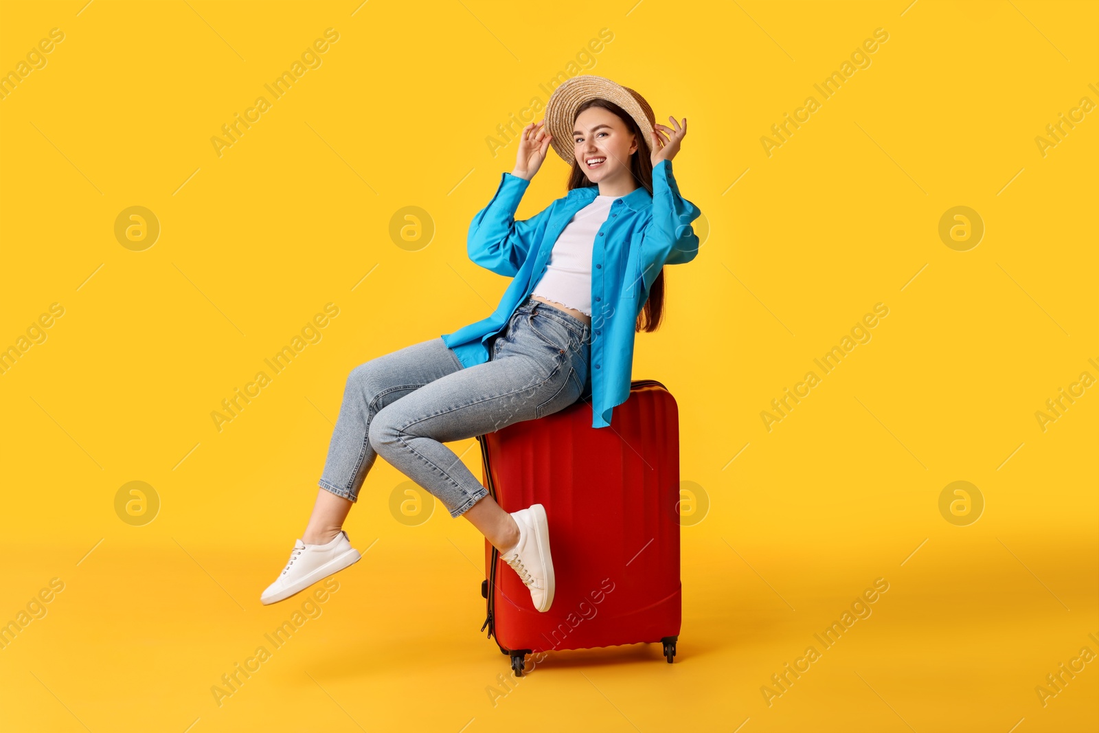 Photo of Woman in straw hat with suitcase on orange background