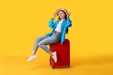 Photo of Woman in straw hat with suitcase on orange background