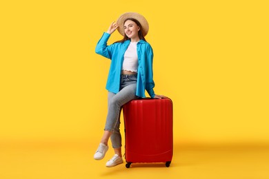 Photo of Woman in straw hat with suitcase on orange background